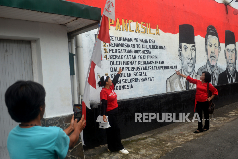 Pengunjung berfoto berlatar lukisan Garuda Pancasila di tembok Dusun Karangwatu, Muntilan, Jawa Tengah, Rabu (1/6/2022). Hari Kelahiran Pancasila momentum untuk mempraktikan nilai luhurnya  