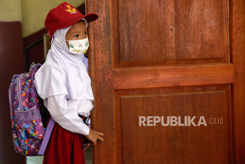 Seorang siswa muda berdiri di depan kelasnya di sebuah sekolah dasar di Depok, Indonesia, 03 Januari 2022.