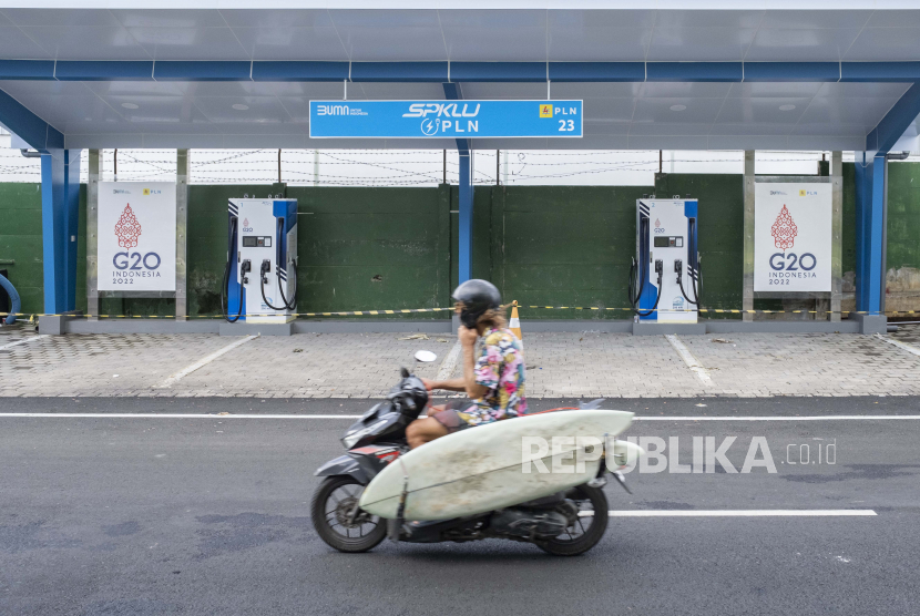  Seorang pria mengendarai skuter melewati stasiun pengisian kendaraan listrik umum yang baru dibangun. Gubernur Jatim Khofifah Indar Parawansa dorong warga untuk beralih kendaraan listrik.