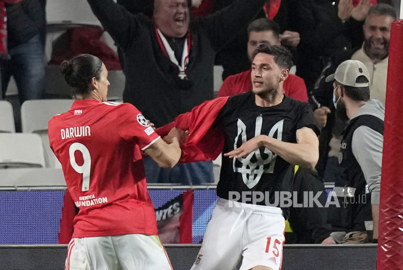 Pemain Benfica Darwin Nunez, kiri, membantu rekan setimnya Roman Yaremchuk, dari Ukraina, melepas kausnya setelah mencetak gol kedua timnya, untuk memperlihatkan kaus dengan lambang Ukraina, juga dikenal sebagai tryzub, selama babak 16 besar Liga Champions, leg pertama, pertandingan sepak bola antara Benfica dan Ajax di stadion Luz di Lisbon, beberapa waktu lalu.. 