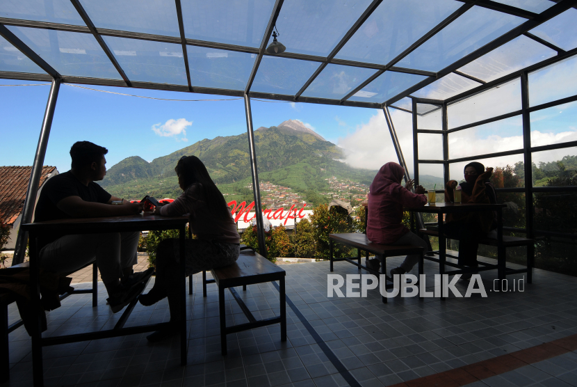 Sejumlah pengunjung kafe menikmati suasana pemandangan Gunung Merapi di Selo, Boyolali, Jawa Tengah, Jumat (10/7/2020). Munculnya klaster keluarga dalam penyebaran Covid-19 dipicu oleh aktivitas di luar rumah yang tak memerhatikan protokol kesehatan.