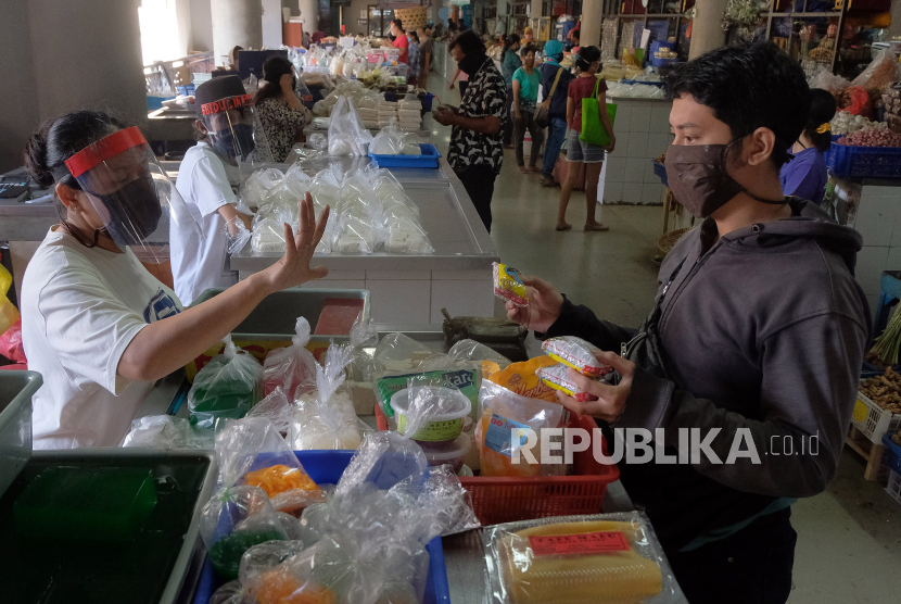 Pedagang menggunakan alat pelindung wajah saat melayani pembeli pada hari pertama Pembatasan Kegiatan Masyarakat (PKM) di Pasar Badung, Denpasar, Bali, Jumat (15/5/2020). Pedagang di pasar-pasar tradisional di Denpasar diwajibkan menggunakan alat pelindung wajah dalam penerapan PKM tersebut untuk menghentikan penyebaran COVID-19