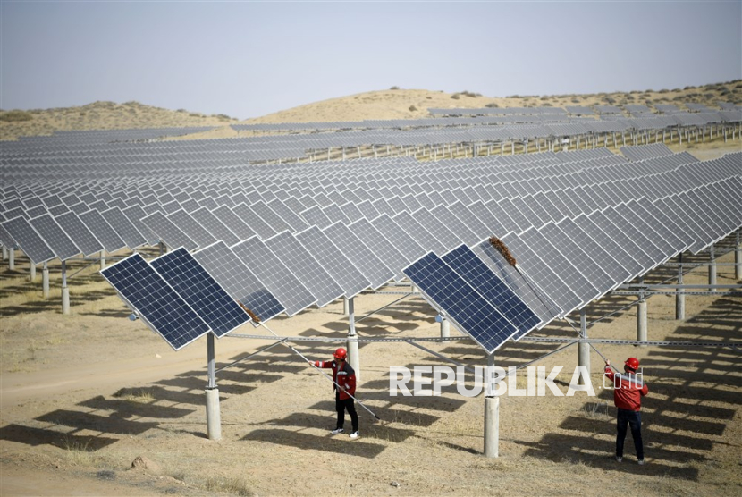  Staff workers clean solar panels after a windy day at a photovoltaic power station in Yinchuan, northwest China