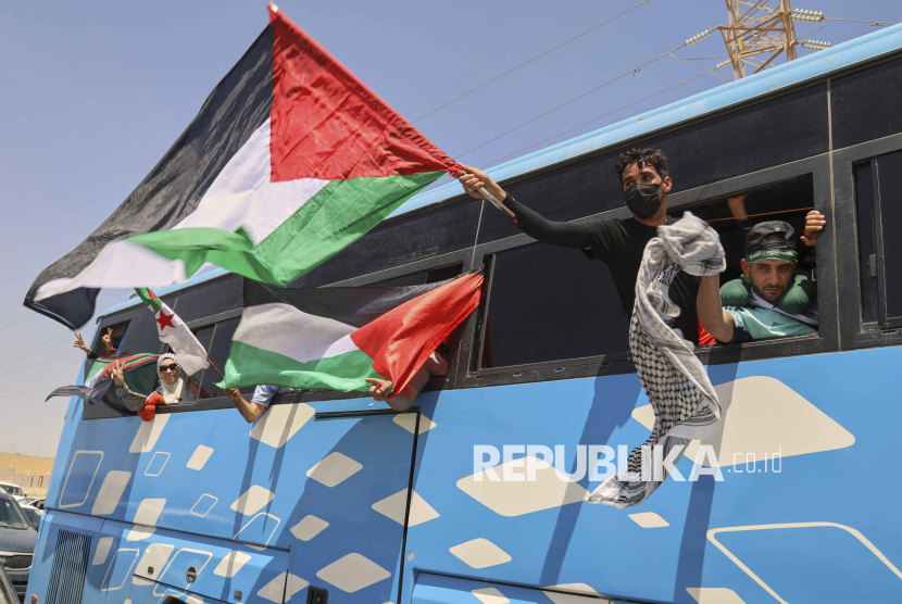 Anggota konvoi kemanusiaan yang berjumlah sedikitnya 1.500 orang, termasuk aktivis dan pendukung dari Aljazair dan Tunisia, melambaikan bendera Palestina dari sebuah bus saat kelompok tersebut melakukan perjalanan menuju Gaza melalui Penyeberangan Rafah Mesir, di Zawiya, Libya, Selasa (10/6/2025).