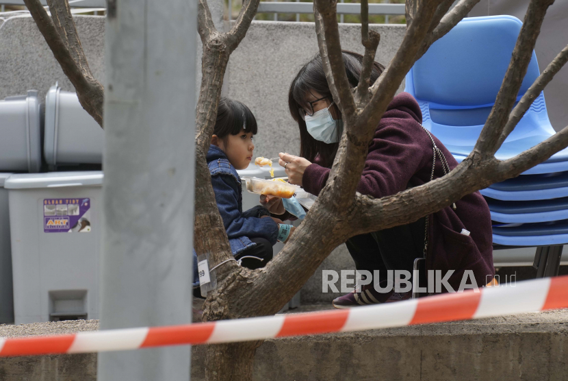  Seorang wanita memberi makan seorang anak di dekat area penampungan di luar Caritas Medical Center di Hong Kong Rabu, 16 Februari 2022. Komisi Kesehatan Nasional (NHC) Cina mengatakan Covid-19 berkontribusi pada penurunan angka kelahiran dan pernikahan di negara itu. 