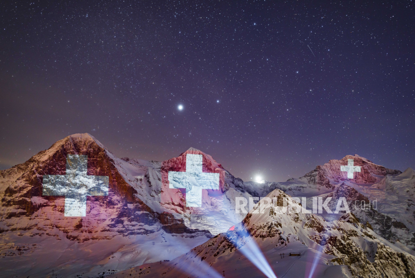  Proyeksi raksasa bendera Swiss di pegunungan Eiger (kiri), Monch (tengah) dan Jungfrau (kanan), oleh seniman cahaya Swiss Gerry Hofstetter.