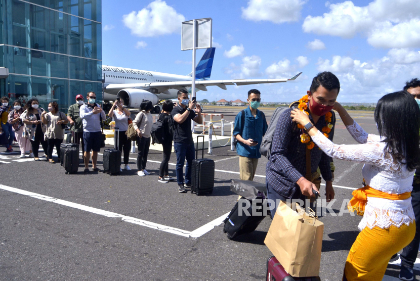Petugas mengalungkan bunga untuk menyambut penumpang pesawat rute domestik yang tiba di Bandara Internasional I Gusti Ngurah Rai, Badung, Bali, Jumat (31/7/2020). Pemprov Bali mulai membuka sektor pariwisata bagi wisatawan domestik pada Jumat (31/7) dengan sejumlah persyaratan yang mengedepankan aspek kesehatan dan kualitas untuk memberi pelindungan, kenyamanan dan keamanan bagi wisatawan yang berkunjung selama masa pandemi COVID-19. 