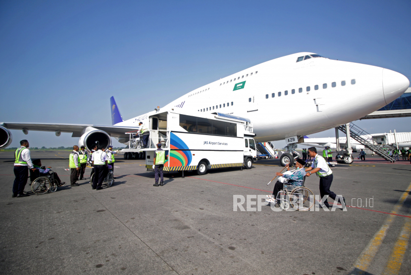 Petugas mendorong kursi roda seorang jamaah calon haji kelompok terbang (kloter) pertama embarkasi Surabaya saat akan menaik pesawat di Bandara Internasional Juanda Surabaya.