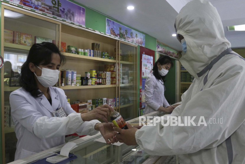  Seorang karyawan Kantor Manajemen Obat Distrik Daesong di Pyongyang memberikan obat kepada seorang penduduk saat negara meningkatkan langkah-langkah untuk menghentikan penyebaran penyakit di Pyongyang, Korea Utara, Senin, 16 Mei 2022.