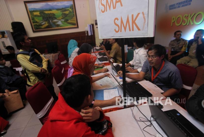 Panitia pelaksana melayani antrean wali murid saat pendaftaran PPDB Online di SMKN 1, Jakarta, Selasa (26/6).