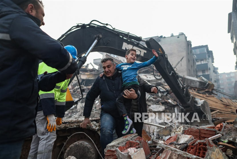 Yigit Cakmak (Tengah) yang berusia delapan tahun bereaksi setelah diselamatkan dari lokasi bangunan yang runtuh, sekitar 52 jam setelah gempa besar, di Hatay, Turki, Rabu (8/2/2023).Lebih dari 7.000 orang tewas dan ribuan lainnya terluka setelahnya dua gempa besar melanda Turki selatan dan Suriah utara pada Senin (6/2/2023).