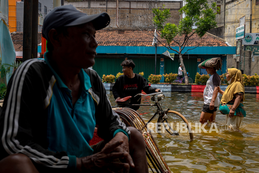 Warga melewati banjir di Jalan Sultan Fatah, Demak, Jawa Tengah, Selasa (19/3/2024). Bencana banjir karena curah hujan tinggi beberapa hari sejak Rabu (13/3) dari hulu ke hilir yang dipengaruhi bibit siklon tropis itu mengakibatkan sejumlah tanggul sungai jebol dan melimpas sehingga menyebabkan beberapa ruas jalan protokol di pusat kota terendam banjir dengan ketinggian sekitar 30-60 cm yang menghambat aktivitas serta mobilitas warga dan sejumlah pertokoan terpaksa tutup. 