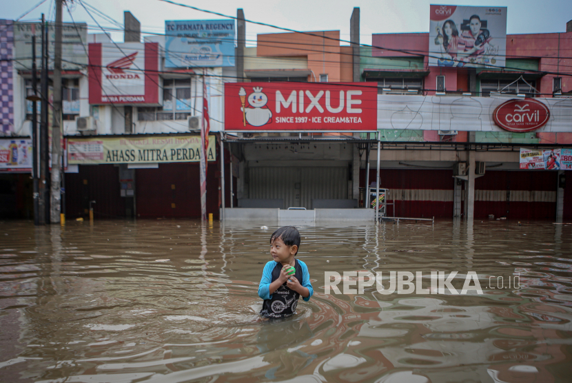 Seorang bocah berjalan di tengah banjir di Pasar Kemis, Kabupaten Tangerang, Banten. Pemkab Tangerang melakukan normalisasi belasan saluran air.