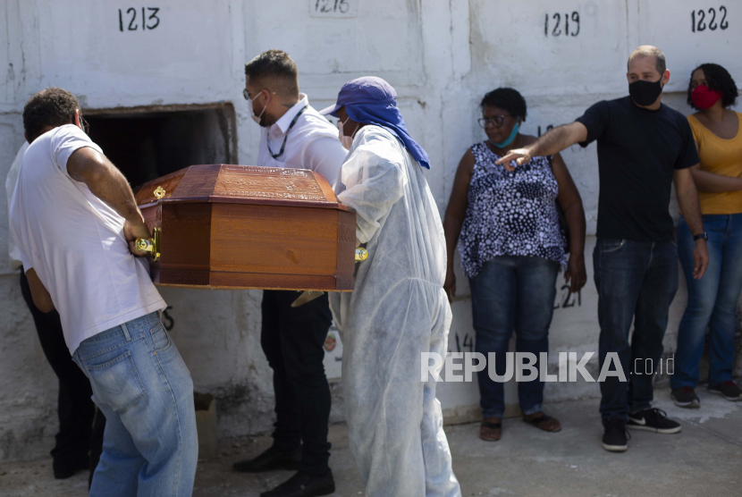 Peti mati yang berisi jenazah Aparecida de Freitas, 41, yang meninggal karena komplikasi terkait COVID-19, ditempatkan di kuburan yang dihadiri oleh suaminya Carlos Alberto, di sebelah kanan mengenakan masker pelindung wajah hitam, di pemakaman Inhauma. , di Rio de Janeiro, Brasil, Kamis, 15 April 2021.