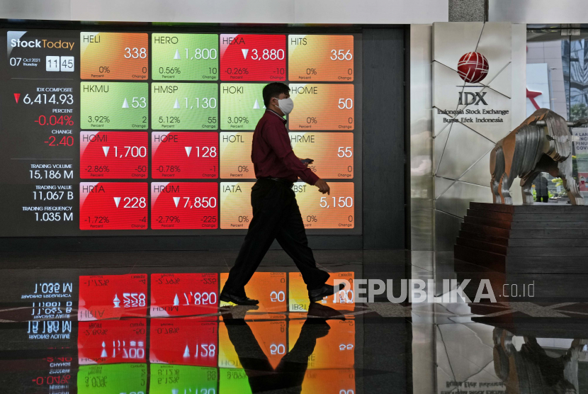 Seorang pria berjalan melewati papan elektronik yang menampilkan harga saham di Bursa Efek Indonesia, di Jakarta, Indonesia. ilustrasi