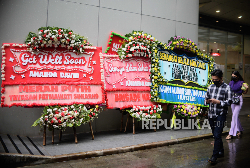 Warga berjalan di dekat karangan bunga dukungan untuk Cristalino David Ozora di Jakarta. Netizen kembali mendoakan kesembuhan David, korban penganiayaan Mario Dandy.