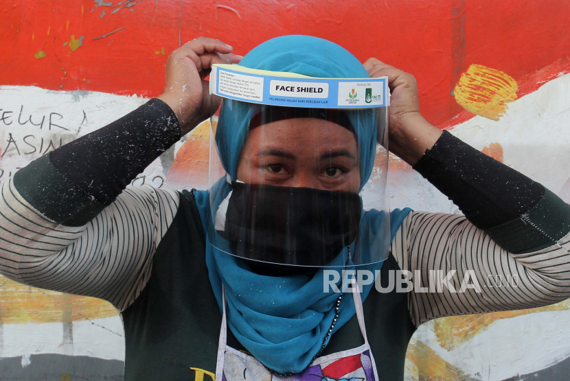 Pedagang memakai alat pelindung wajah (face shield) yang didapat dari pembagian Alat Pelindung Diri (APD) di Pasar Keputih, Surabaya, Jawa Timur, Ahad (28/6). Kementerian Perdagangan (Kemendag) berkomitmen mendorong kinerja ekspor di tengah pandemi Covid-19 saat ini. Salah satunya dengan menerbitkan Permendag Nomor 57 Tahun 2020 tentang Ketentuan Ekspor Bahan Baku Masker, Masker, dan Alat Pelindung Diri, yang sudah mulai berlaku pada 19 Juni 2020.