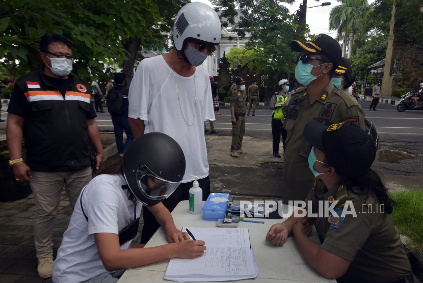 Petugas menindak warga negara asing yang melanggar protokol kesehatan dalam Pemberlakuan Pembatasan Kegiatan Masyarakat (PPKM) di Denpasar, Bali, Selasa (12/1/2021). Satpol PP Provinsi Bali memberikan sanksi administrasi berupa denda Rp100 ribu dan sanksi sosial bagi pelanggar protokol kesehatan COVID-19. 