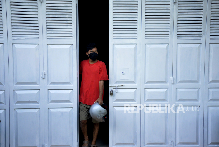 Seorang warga yang mengenakan masker keluar dari ruko di Makassar, Sulawesi Selatan, Kamis (16/4/2020). Menteri Kesehatan menyetujui penerapan Pembatasan Sosial Berskala Besar (PSBB) di Makassar dalam percepatan penanganan COVID-19