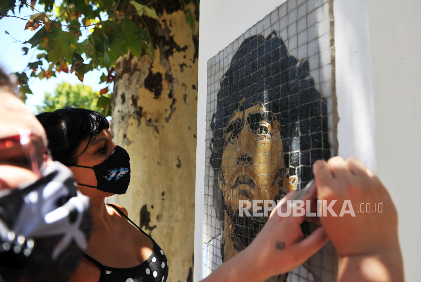 Paula Soto dan Gabriela Pereyra membersihkan mosaik wajah Diego Armando Maradona bagian dari kolektif Mosaico Nacional, di lingkungan Parque Chas, di Buenos Aires, Argentina, 25 Januari 2021. 