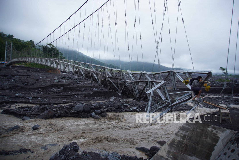 Warga melintas di Jembatan Gantung Kaliregoyo di Dusun Sumberwuluh, Candipuro, Lumajang, Jawa Timur, Sabtu (8/7/2023). Jembatan yang memiliki panjang 198 meter dan menjadi penghubung Desa Jugosari dengan Desa Sumberwuluh. tersebut putus akibat diterang banjir lahar hujan pada Jumat (7/7) . 