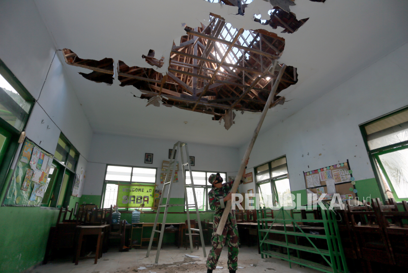 Personel TNI membersihkan puing di salah satu ruang kelas MI Hidayatullah Blitar yang rusak akibat gempa di Jawa Timur, Ahad (11/4/2021). BPBD Kota dan Kabupaten Blitar merilis sebanyak 325 bangunan rusak, dan 13 orang mengalami luka-luka di 24 kecamatan akibat dampak gempa bermagnitudo 6,1 di lepas pantai Malang pada Sabtu (10/4). 