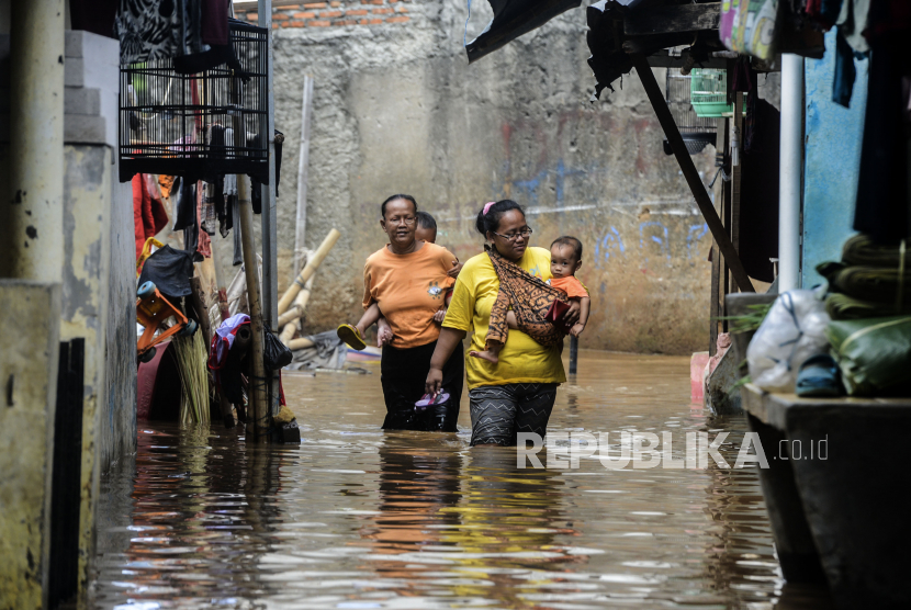 Sejumlah warga melintasi genangan air saat banjir di menggenangi Kebon Pala, Kampung Melayu, Jatinegara, Jakarta Timur.