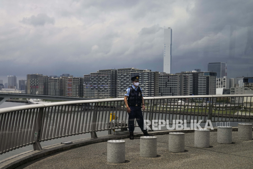  Seorang petugas polisi berjaga di jembatan yang menghadap ke desa atlet untuk Olimpiade dan Paralimpiade Musim Panas 2020, Kamis, 15 Juli 2021, di Tokyo. 
