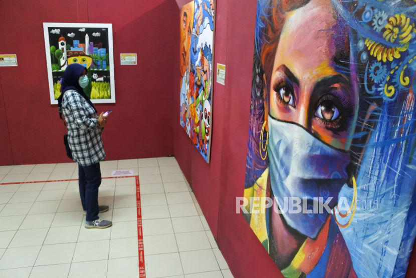 Pengunjung mengamati karya seni lukis pada pameran seni rupa bertajuk Pagebluk di salah satu pusat perbelanjaan Jember, Jawa Timur, Rabu (26/8/2020). Pameran Pagebluk tersebut mengangkat tema pandemi COVID-19 dengan menampilkan 60 karya seni lukis. 