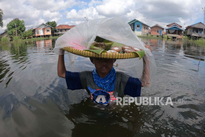 Seorang bocah menerobos banjir luapan Sungai Batanghari yang menggenangi permukiman untuk berjualan di Pelayangan, Jambi