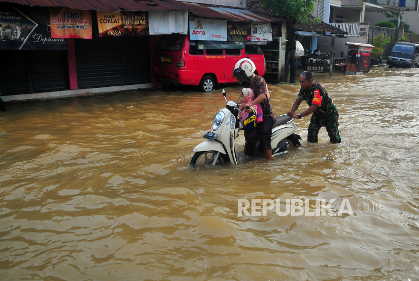 Anggota TNI mendorong kendaraan bermotor warga yang mogok saat melintasi jalan yang tergenang banjir di Kudus, Jawa Tengah (ilustrasi) 