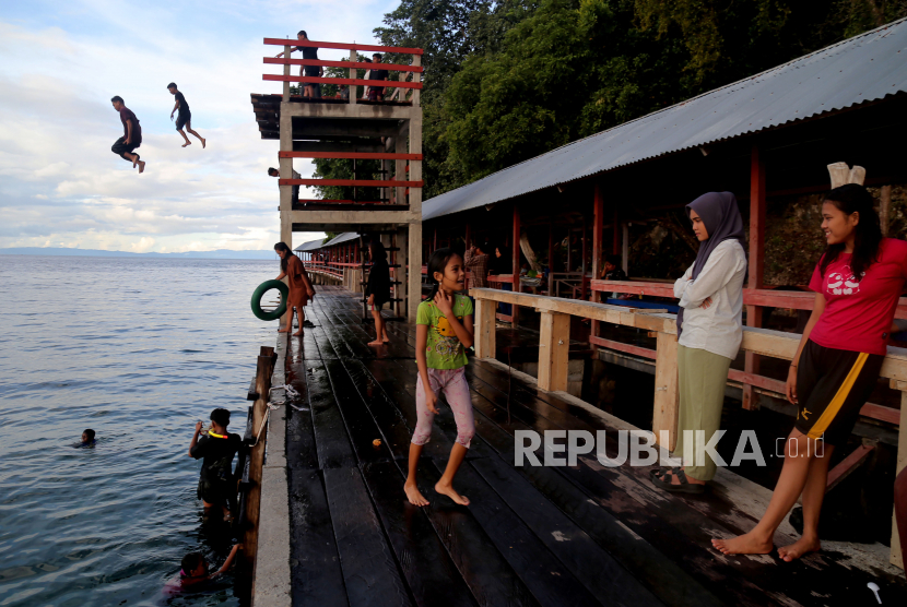Pengunjung melompat dari atas dermaga di Pantai Sibela, Desa Babang, Kabupaten Halmahera, Maluku Utara, Ahad (2/7/2023). Kunjungan wisatawan mancanegara pada Mei mencapai 945,59 ribu orang.