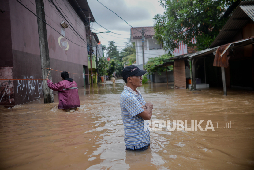 Warga berjalan melintasi banjir yang merendam kawasan Cipinang Melayu, Jakarta Timur, Jumat (19/2). Banjir yang terjadi akibat  luapan Kali Sunter tersebut menggenangi sebanyak lima Rukun tetangga diantaranya RT 01 hingga RT 05 yang bread di RW 04 dengan ketinggian 90 centimeter.