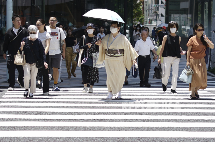 Orang-orang menggunakan payung saat cuaca panas di Tokyo, Jepang, Juni 2024.