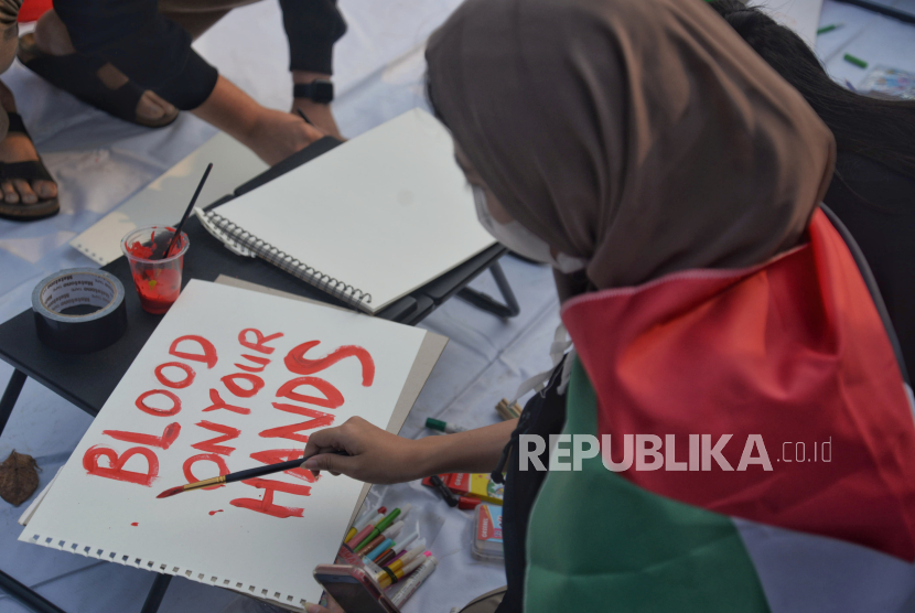 Sejumlah orang menuliskan kata-kata kecaman dalam aksi solidaritas untuk palestina bertajuk All Eyes On Rafah di Seberang Kedubes AS, Jakarta, Jumat (31/5/2024).