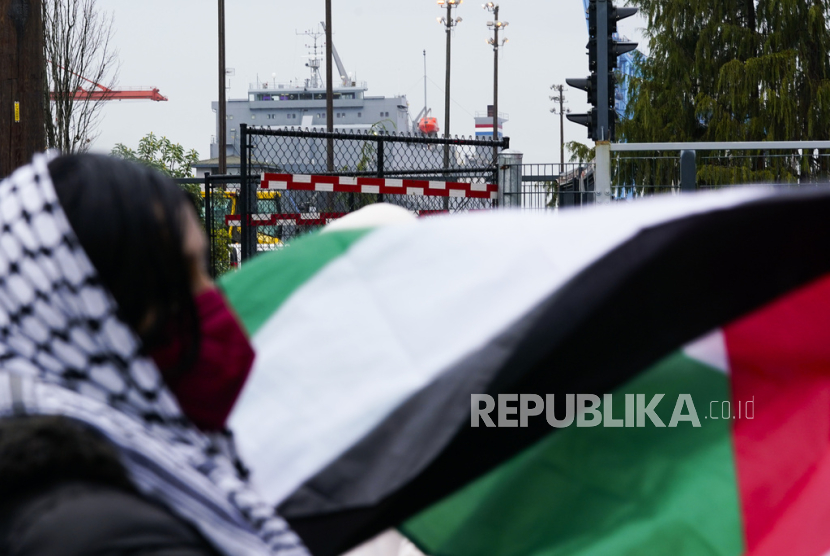 Seorang pengunjuk rasa memegang bendera Palestina di depan kapal kargo MV Cape Orlando ketika orang-orang memblokir pintu masuk Pelabuhan Tacoma dalam upaya untuk menunda kapal kargo MV Cape Orlando, di Tacoma, Washington, Amerika Serikat, Senin (6/11/2023). 