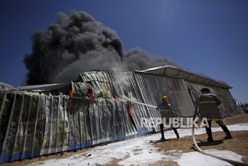  Petugas pemadam kebakaran Palestina bekerja untuk memadamkan api di pabrik cat setelah dilanda serangan udara Israel, di Rafah, Jalur Gaza, Selasa, 18 Mei 2021.