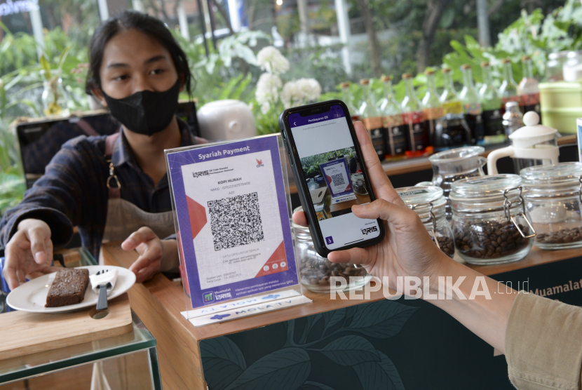 Seorang pelanggan memindai kode batang Quick Response Code Indonesian Standard (QRIS) dengan gawainya saat transaksi melalui aplikasi digital perbankan Bank Muamalat di sebuah kedai kopi di Jakarta, Jumat (28/1/2022). Bank Indonesia memperkirakan transaksi digital banking pada tahun 2022 akan mencapai Rp49.733,8 triliun atau tumbuh 24,83 persen secara tahunan (yoy) bila dibandingkan tahun 2021 yang mencapai Rp39.841,4 triliun. 