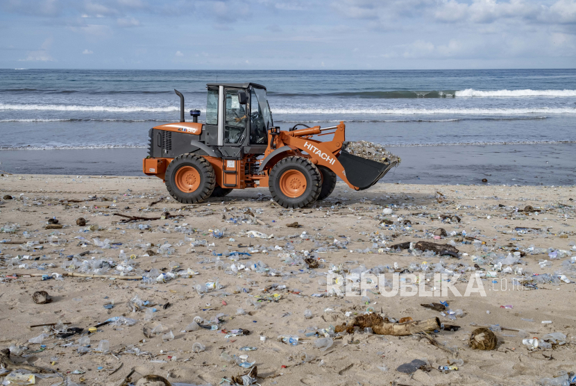  Pekerja membersihkan tumpukan puing dan sampah plastik yang dibawa oleh gelombang kuat di Pantai Kuta di Bali, Indonesia, 1 Januari 2021. 