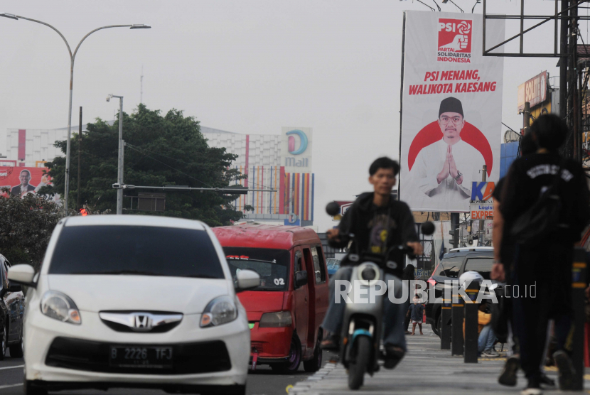 Warga melintas menggunakan sepeda listrik di dekat baliho bergambar Kaesang Pangarep di Jalan Margonda Raya, Depok. Dewan Dakwah Islamiyah Depok sebut Kaesang belum mampu menyelesaikan urusan bisnis.