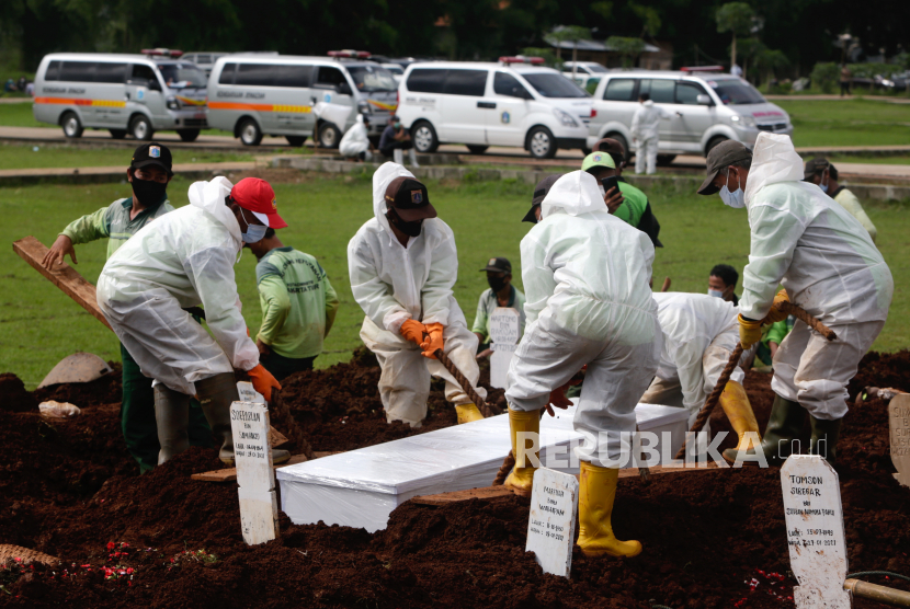 Pekerja yang mengenakan jas hazmat membawa peti mati korban Covid-19 saat pemakaman di TPU Bambu Apus, Jakarta.