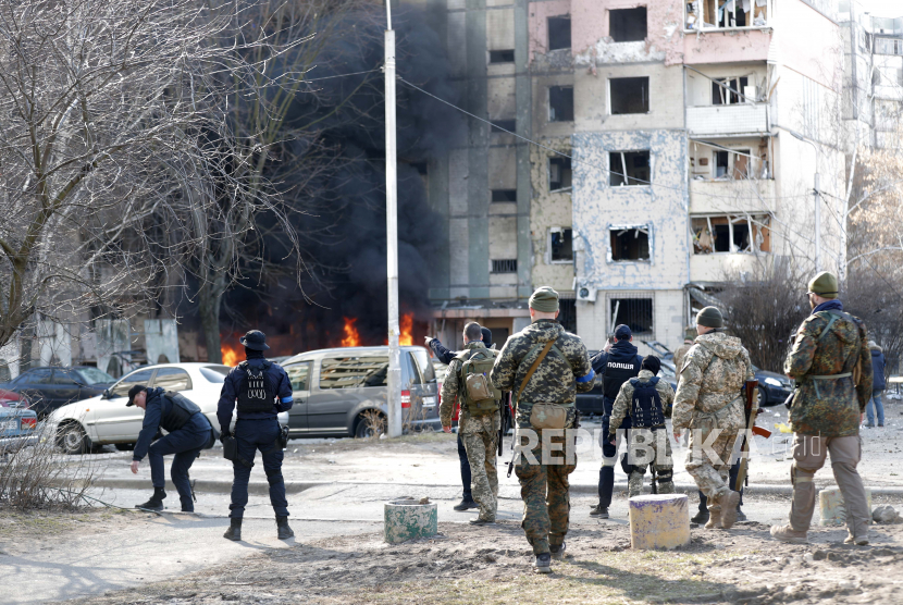 Petugas pemadam kebakaran dan tim keamanan Ukraina di lokasi sebuah gedung yang terkena rudal Rusia di Kyiv (Kiev), Ukraina, 20 Maret 2022. AS mengevakuasi diplomat-diplomatnya di awal perang tiga bulan yang lalu.