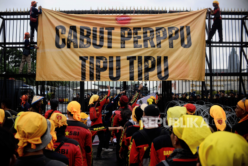 Sejumlah massa aksi memasang spanduk saat unjuk rasa di depan Gedung DPR, Jakarta, Selasa (14/3/2023). Pada unjuk rasa tersebut mereka memprotes dan meminta DPR untuk mencabut Perppu Cipta Kerja dari pengesahan.