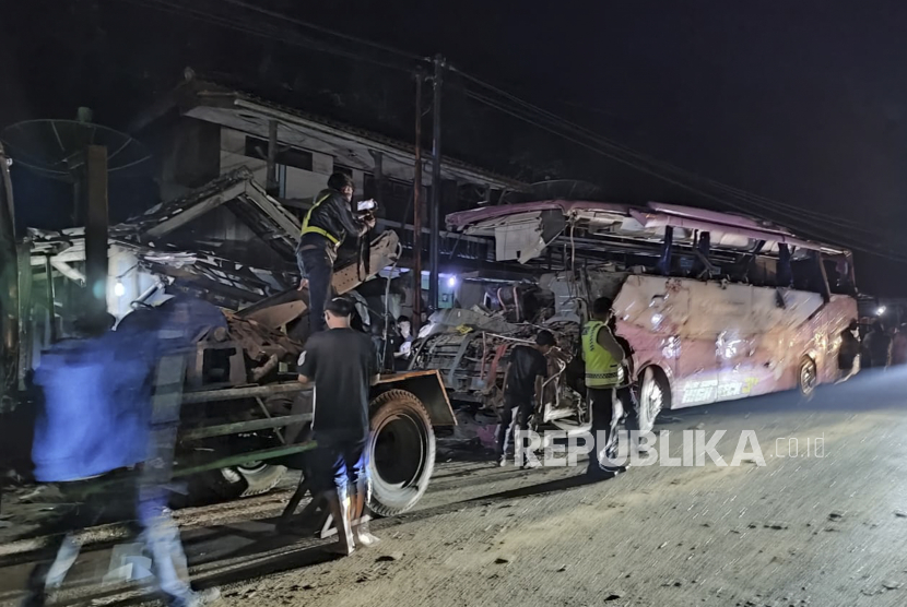 Petugas polisi berjaga jaga di dekat bus Pariwisata yang menabrak rumah warga di Payungsari, Kecamatan  Panumbangan, Kabupaten Ciamis, Jawa Barat, Sabtu (21/5/2022). Sebanyak empat orang tewas dan 24 orang luka-luka dalam kejadian tersebut. 