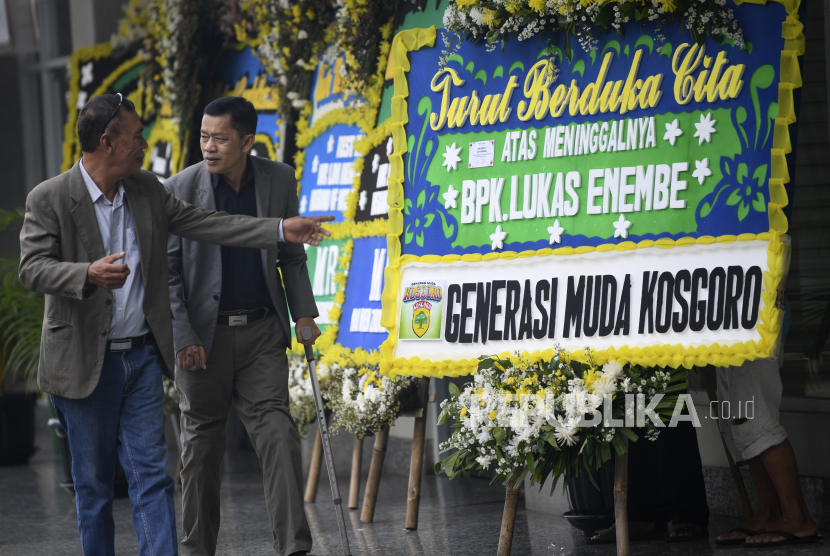 Warga berjalan di depan karangan bunga duka dari mantan Gubernur Papua, Lukas Enembe di Rumah Duka Sentosa, RSPAD Gatot Subroto, Jakarta, Selasa (26/12/2023). 