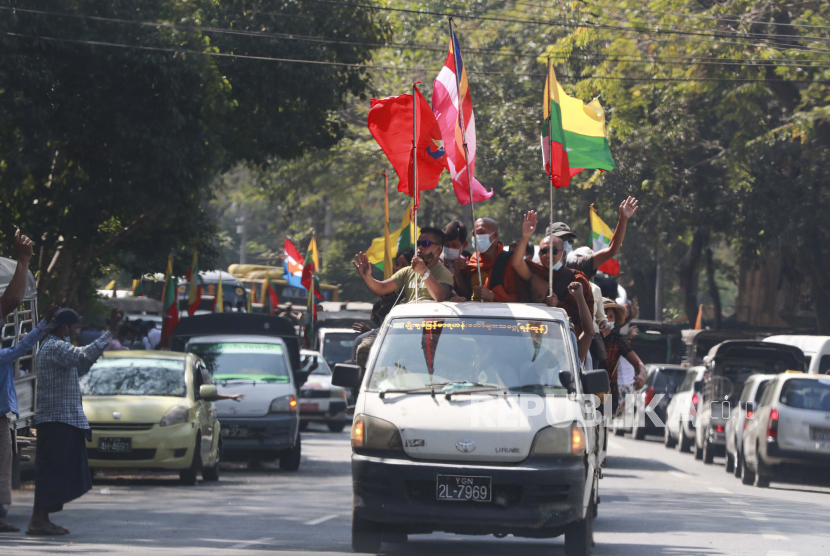  Bendera agama Buddha dan militer dikibarkan oleh para pendukung termasuk biksu Buddha di dalam kendaraan Senin, 1 Februari 2021, di Yangon, Myanmar. Militer Myanmar telah mengumumkan akan mengadakan pemilihan baru pada akhir dari keadaan darurat satu tahun yang diumumkannya Senin ketika mereka menguasai negara itu dan dilaporkan menahan pemimpin Aung San Suu Kyi.
