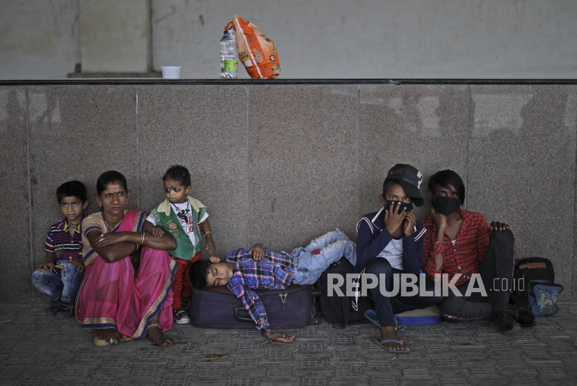 Seorang anak laki-laki tidur diatas koper ketika keluarga migran dari negara bagian lain berusaha untuk pulang dengan menunggu transportasi menuju stasiun kereta api di pinggiran New Delhi, India, Senin (18/5). India telah mencatat rekor lonjakan harian dalam kasus baru virus Corona