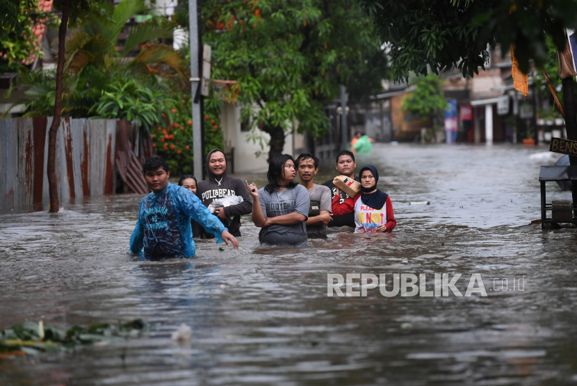 Warga melintasi banjir di Pela Mampang, Jakarta, Ahad (7/11). Sejumlah wilayah di Jakarta terendam banjir akibat intensitas hujan yang tinggi. 