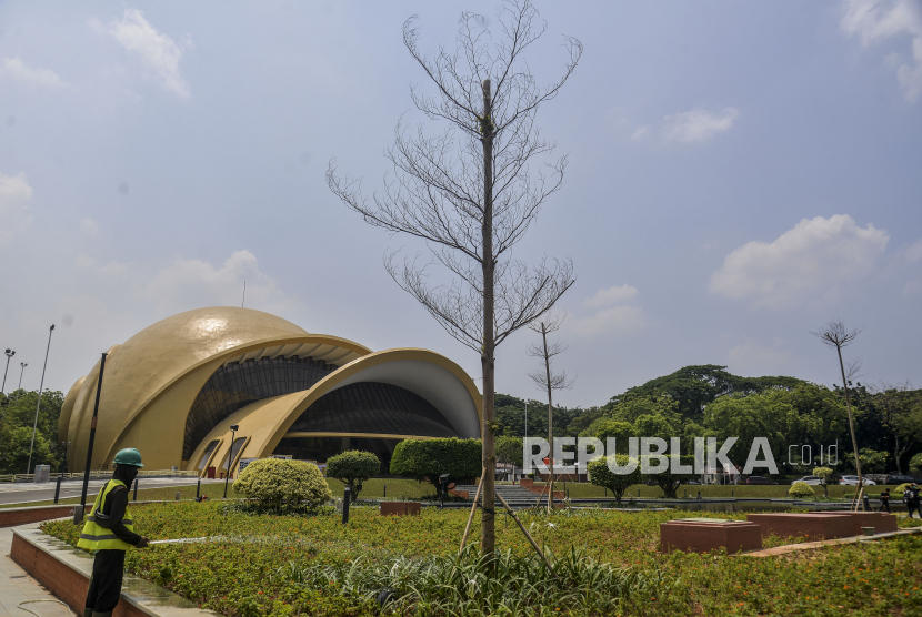 Pekerja menyiram tanaman dengan latar belakang Teater Keong Emas di Taman Mini Indonesia Indah (TMII), Jakarta, Rabu (28/9/2022). Proses revitalisasi TMII telah mencapai 98 persen dan direncanakan akan menjadi salah satu lokasi KTT G20. Republika/Putra M. Akbar