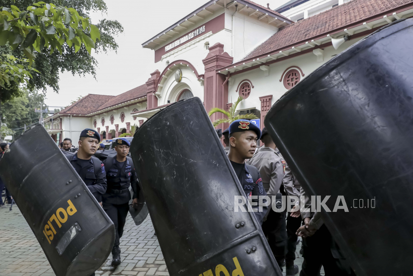  Polisi membawa perisai mereka selama persiapan keamanan untuk sidang pertama penyerbuan stadion Kajuruhan di Surabaya, Jawa Timur. PBSI menilai sidang Tragedi Kanjuruhan tidak berpihak kepada para korban. 